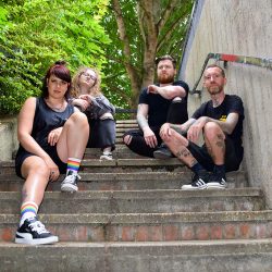 4 band memebers of Millie Manders & the Shut Up sat on concrete steps